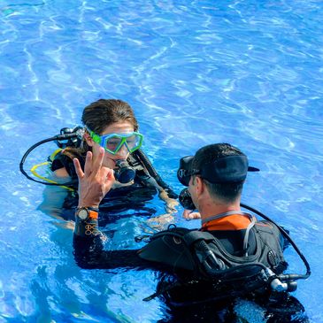 Two divers communicating in a pool.