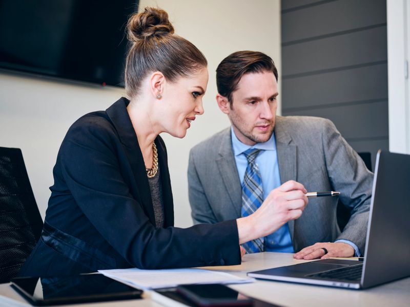 A financial planner meets with a client in an office meeting room environment.