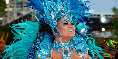 Smiling woman in vibrant blue feathered carnival costume.