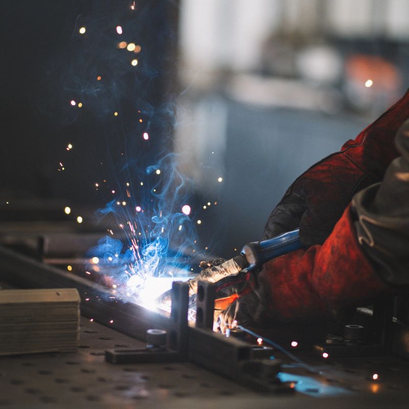Young welder professional working in the factory. Shallow DOF. Developed from RAW; retouched with special care and attention; Small amount of grain added for best final impression.16 bit Adobe RGB color profile.