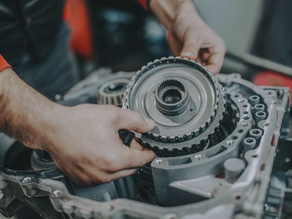 Hands assembling a mechanical gear component in an engine.