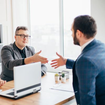 Two businessmen reaching out for a handshake during a meeting in an office.