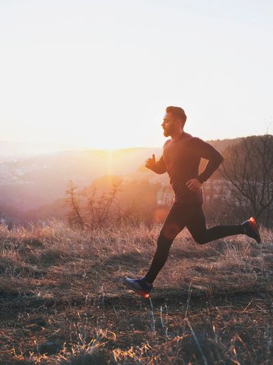 Man jogging outdoors at sunrise in a natural setting.