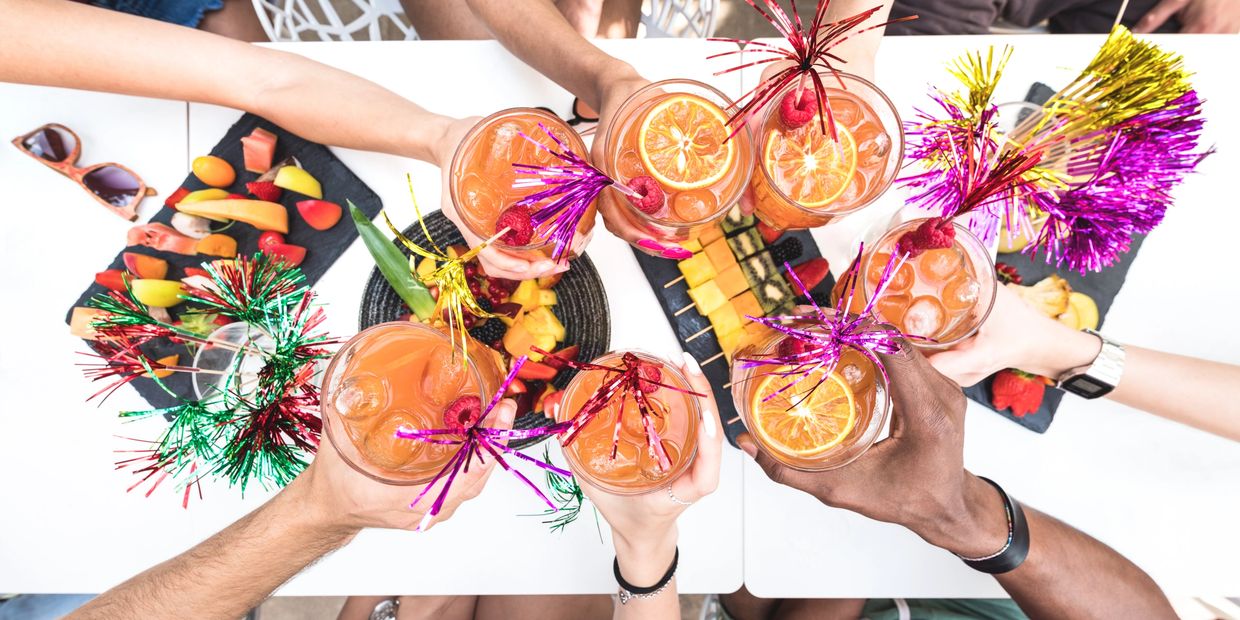 Friends cheers with festive drinks and fruit platters at a celebration.