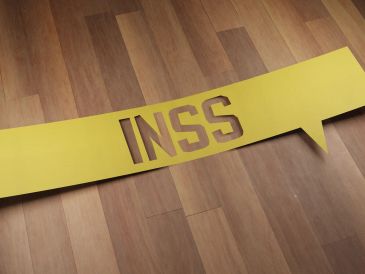 Placa amarela com as letras INSS recortadas.