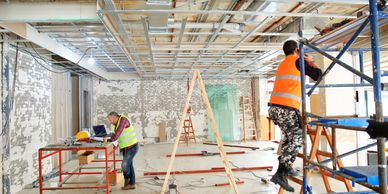 Construction workers renovating an industrial interior space with scaffolding and tools.