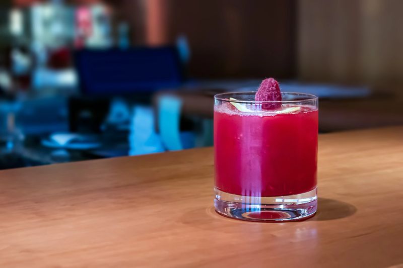 Red Velvet drink - cocktail made with vodka, velvet syrup and a berry on top, closeup, indoors.