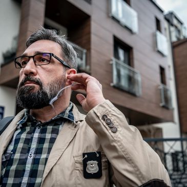 Serious security officer adjusting earpiece outside modern building.
