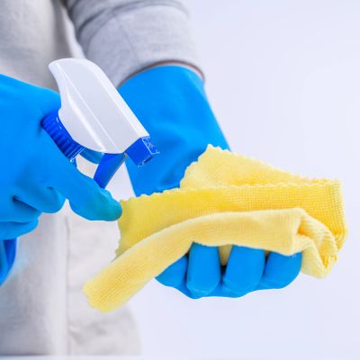 Person cleaning with spray bottle and yellow cloth.