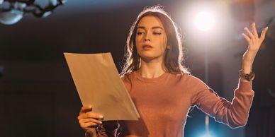 Woman performing a speech or reading on stage.