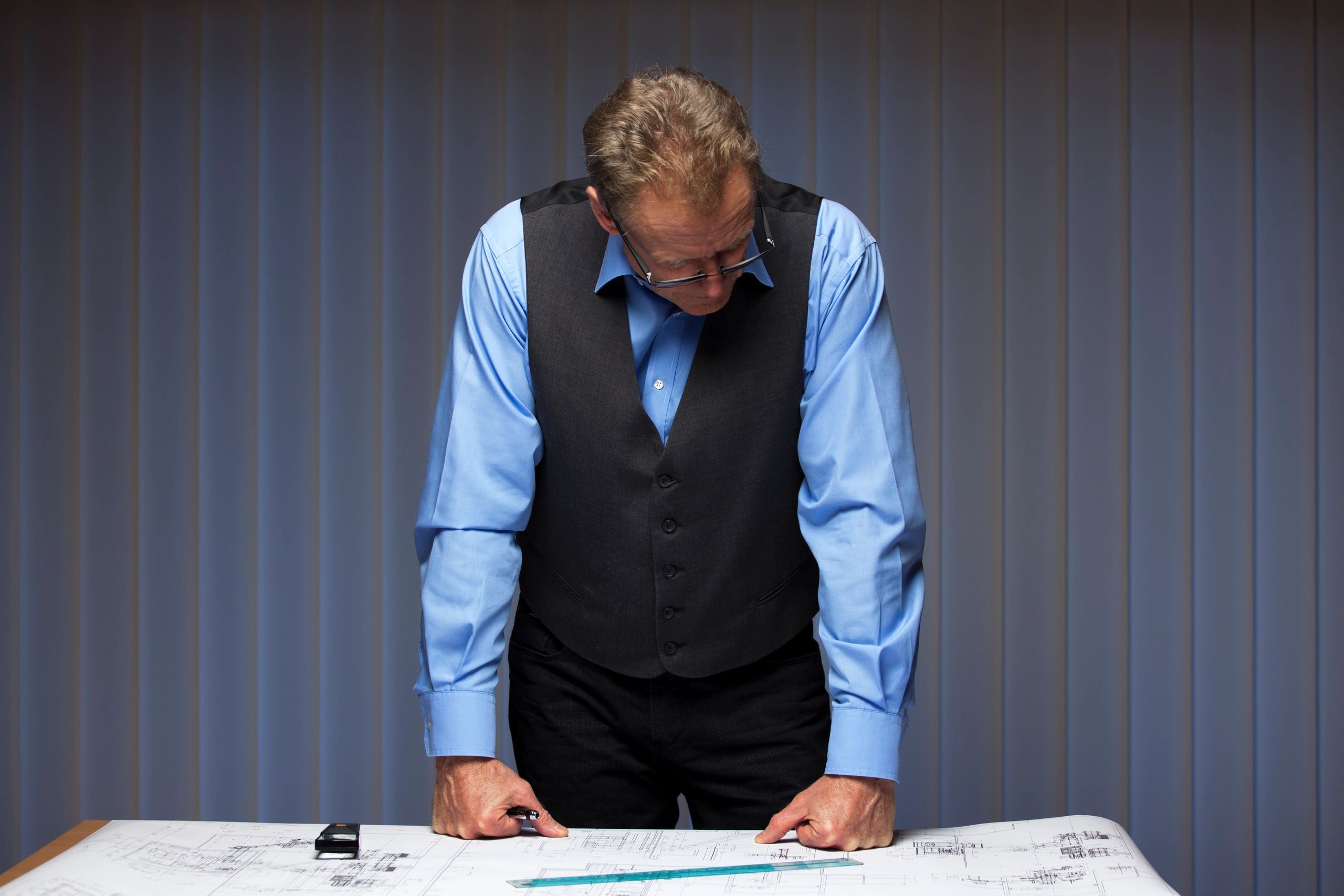 Man studying architectural blueprints with focus.