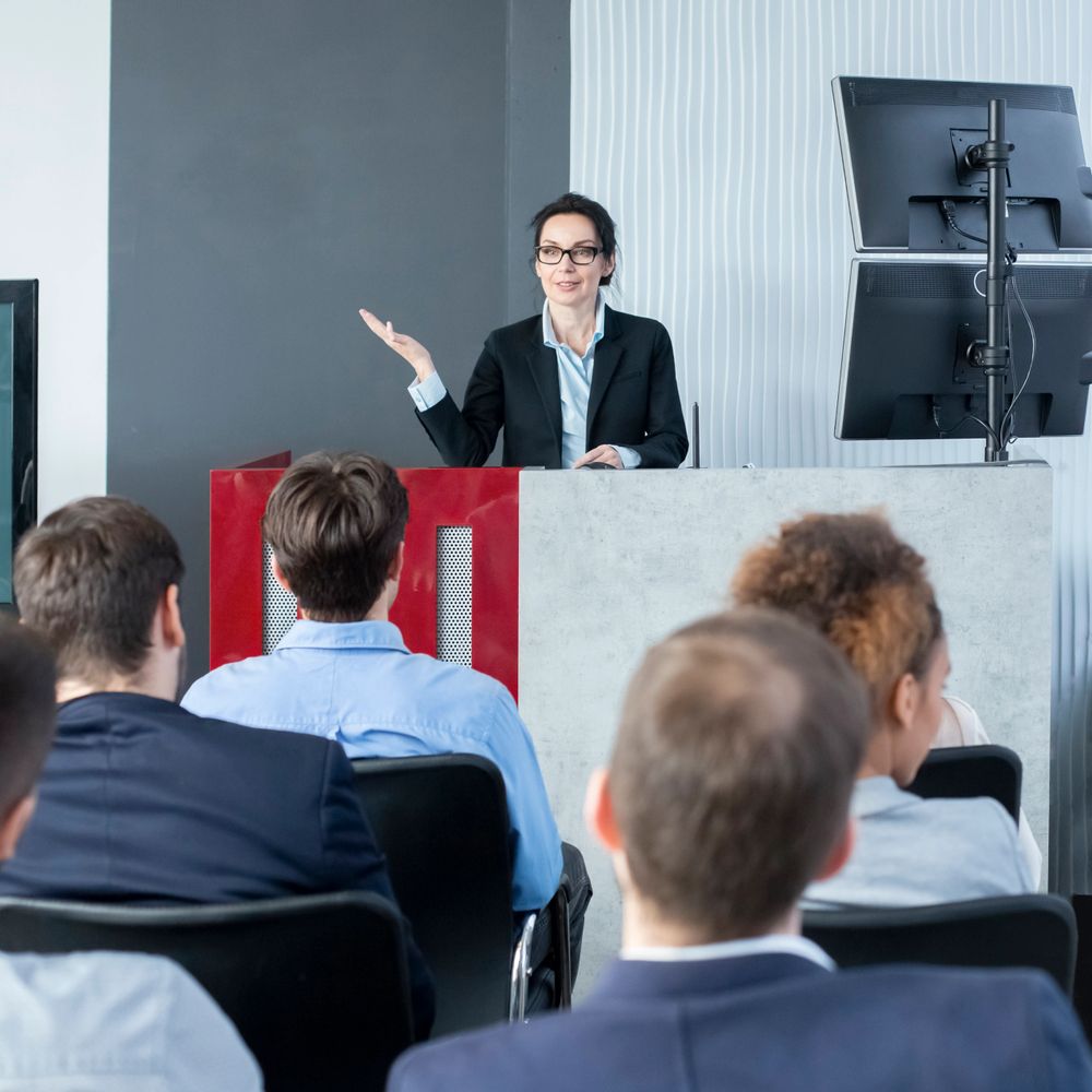 A woman in business attire giving a presentation to an audience.
