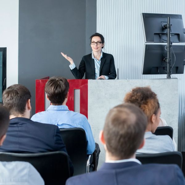 Businesswoman presenting to an attentive audience in a modern conference room.