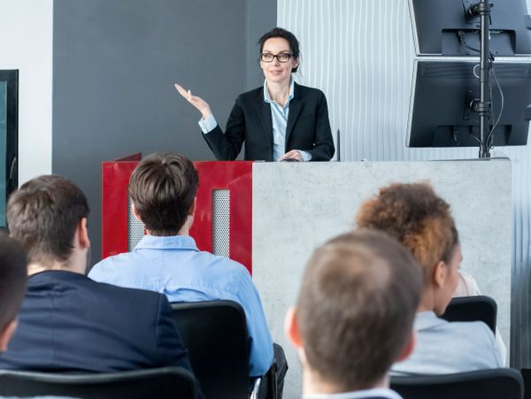 A woman in business attire giving a presentation to an audience.