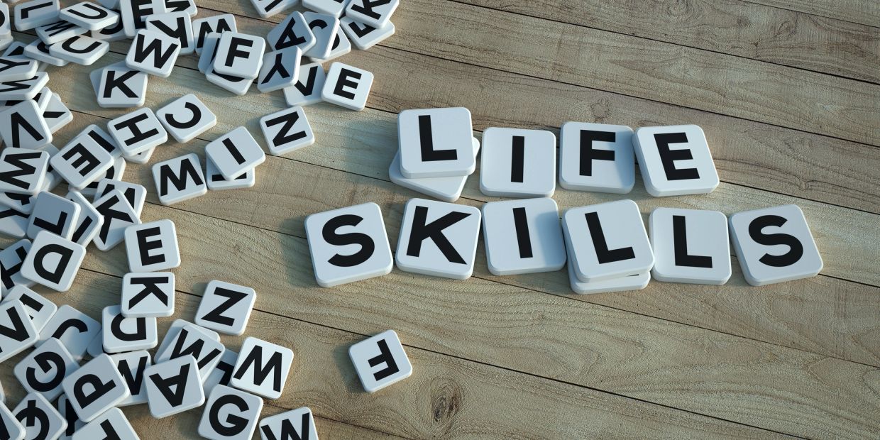 Letter tiles spelling 'LIFE SKILLS' on a wooden surface.