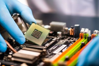 A gloved hand installing a CPU on a motherboard.