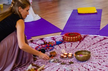 Woman arranging spiritual items on a patterned cloth during a meditation session.