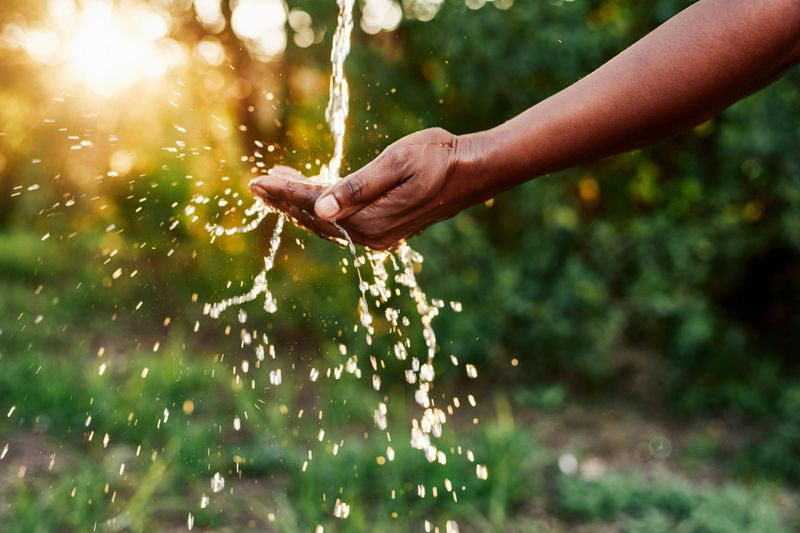 Cropped shot of an unrecognizable woman’s hands under a stream of running water outdoors