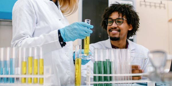 Scientists in lab coats working with colorful test tubes in a laboratory.
