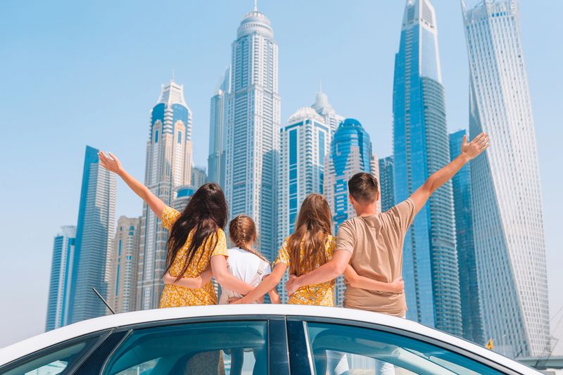 Family of four on car vacation on background of skyscrapers in Dubai