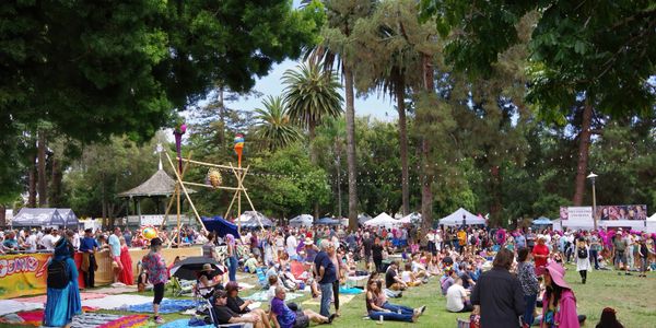 Crowd enjoying a sunny day at an outdoor festival in a park.
