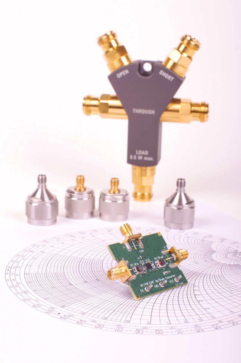Radio frequency mixer printed circuit board in front of Smith chart and other microwave measurement tools