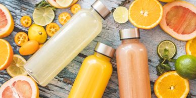 Bottles of fresh citrus juice surrounded by sliced fruits.