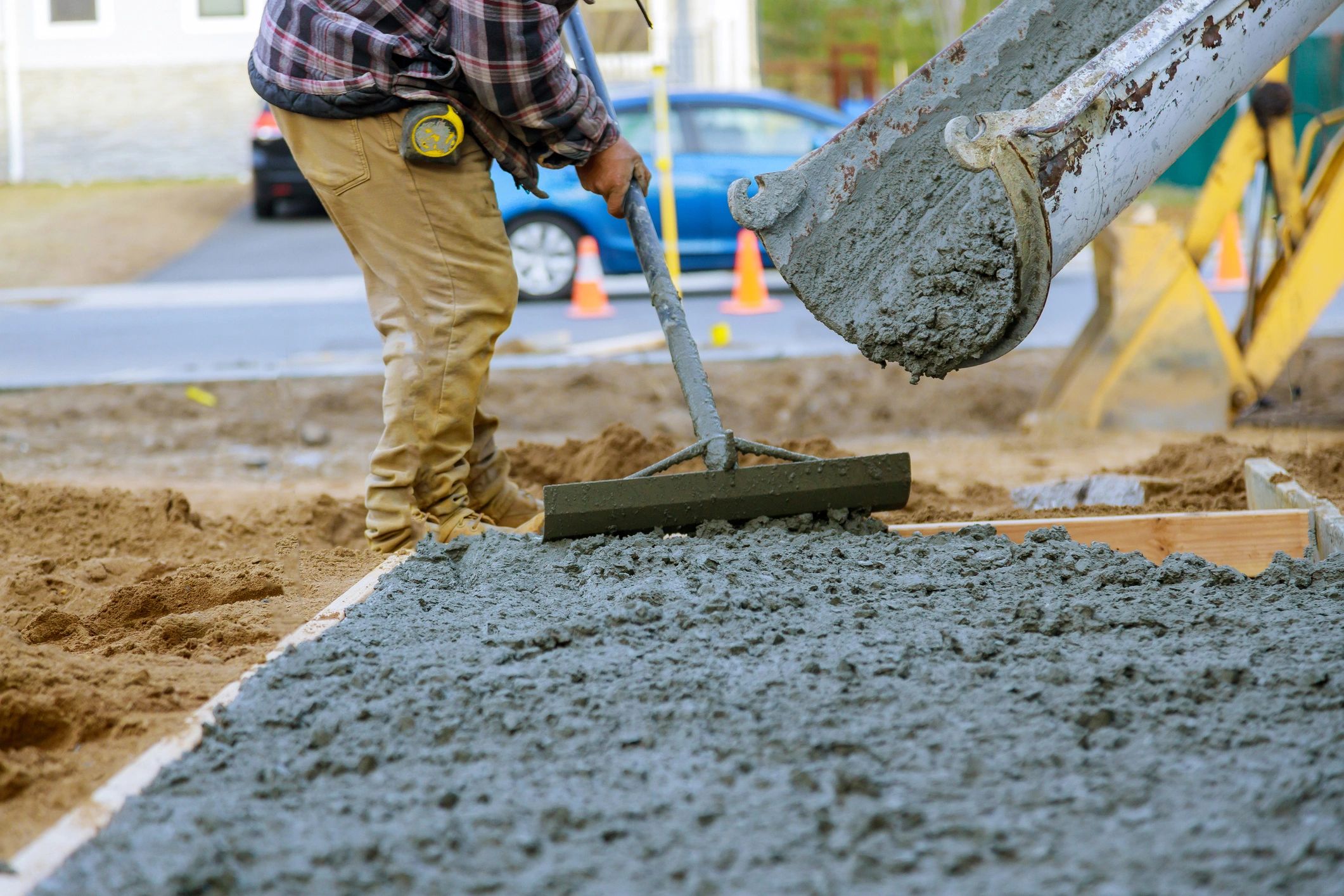 Construction worker leveling freshly poured concrete at a worksite.