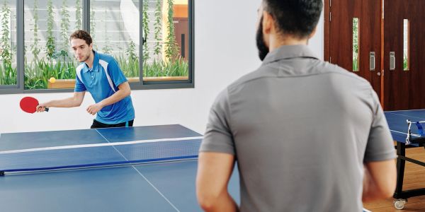 Two men playing table tennis indoors.