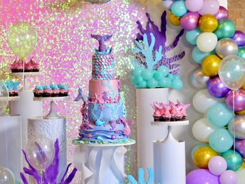 Underwater-themed mermaid cake with matching cupcakes and colorful balloon decorations.