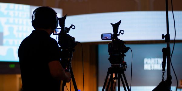 Silhouette of a cameraman filming with two professional cameras indoors.