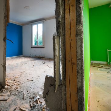 Partially demolished interior wall separating two colorful rooms in disrepair.