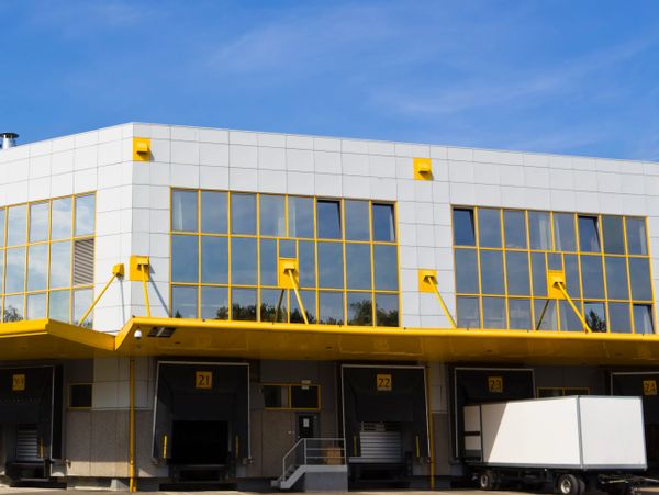 Modern warehouse loading docks with yellow accents and a white truck.