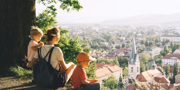 A woman and two children overlooking a town from a hill.