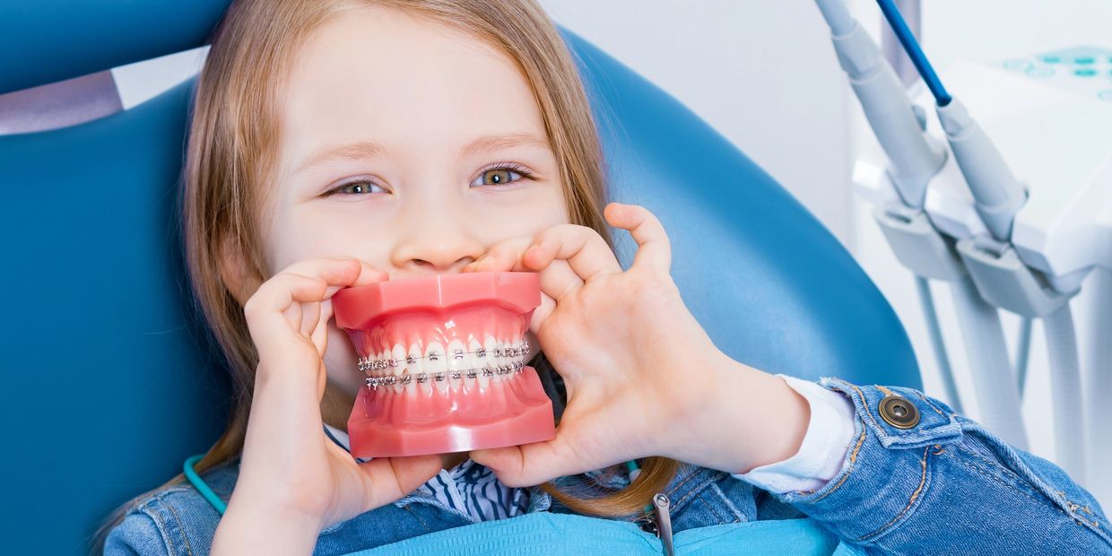 Young girl holding dental braces model at Bar Orthodontics, Rockwall, TX , Early orthodontic care, phase 1, kids braces, expander