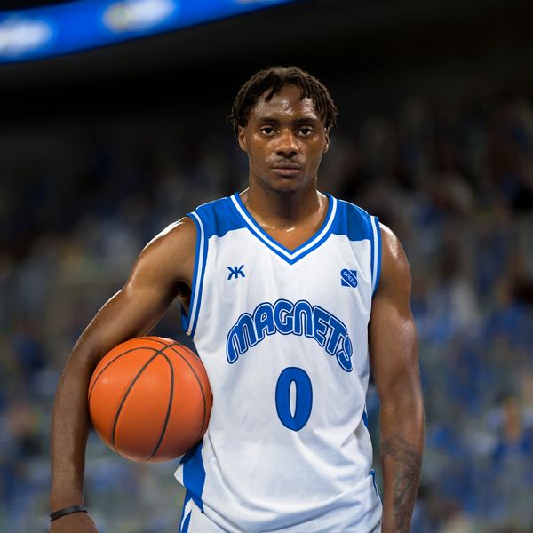 Basketball player in white and blue jersey holding a basketball.