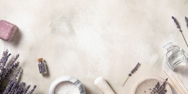 Lavender spa essentials with salt, oil, and mortar on a light surface.