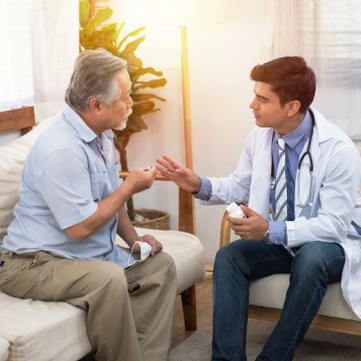 Doctor consulting an elderly man about medication in a cozy room.