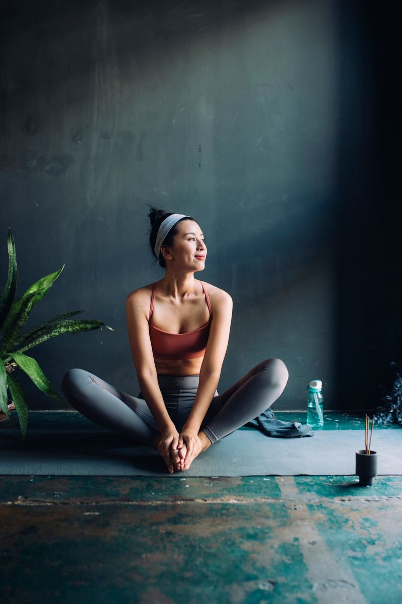 Full-legth shot of a young Asian woman sitting on a yoga mat before exercising.