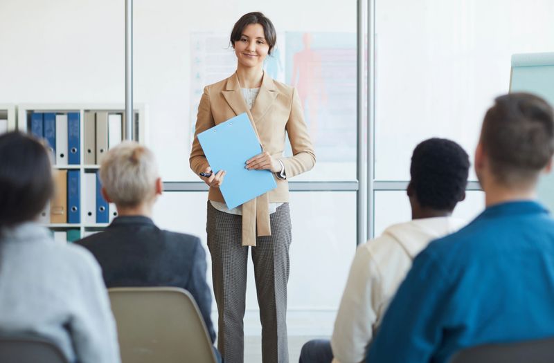 Portrait of successful young businesswoman giving speech to audience during seminar, copy space