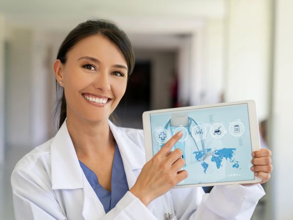 Smiling female doctor holding a tablet with medical icons.