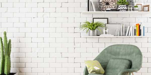 Cozy green armchair with cushions against a white brick wall and decorated shelves.