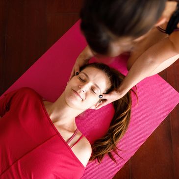 Woman receiving a head massage on a yoga mat.