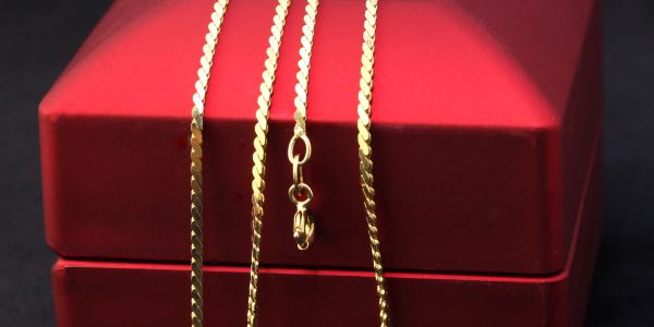 Gold chain necklace on a red box.