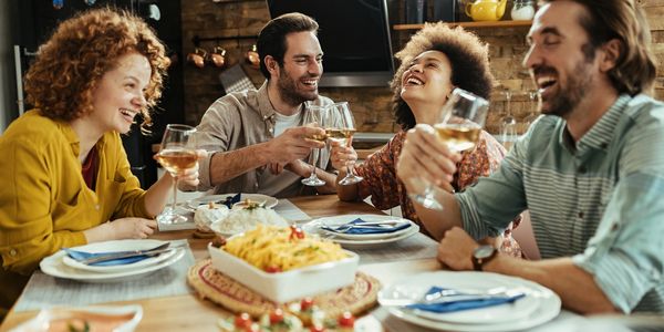 two women and two men sitting at a table laughing and drinking wine