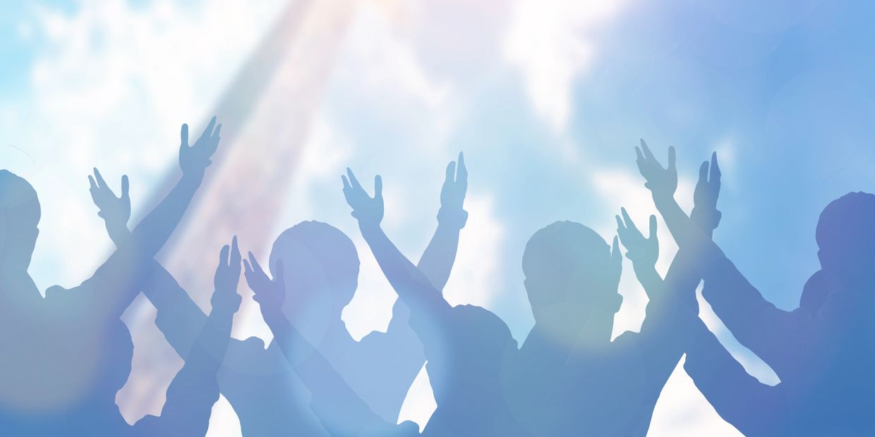 Silhouettes of people raising hands under sky light.