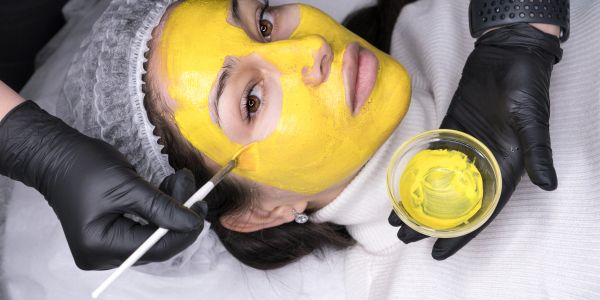 Woman having a yellow facial mask applied.