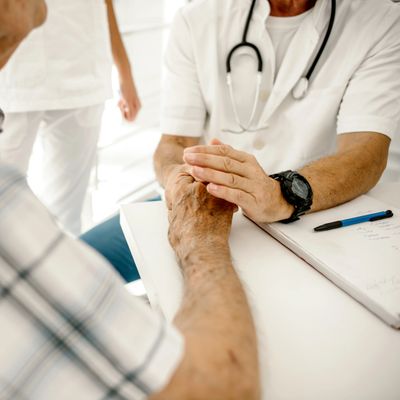 Doctor gently holding an elderly patient's hand during consultation.