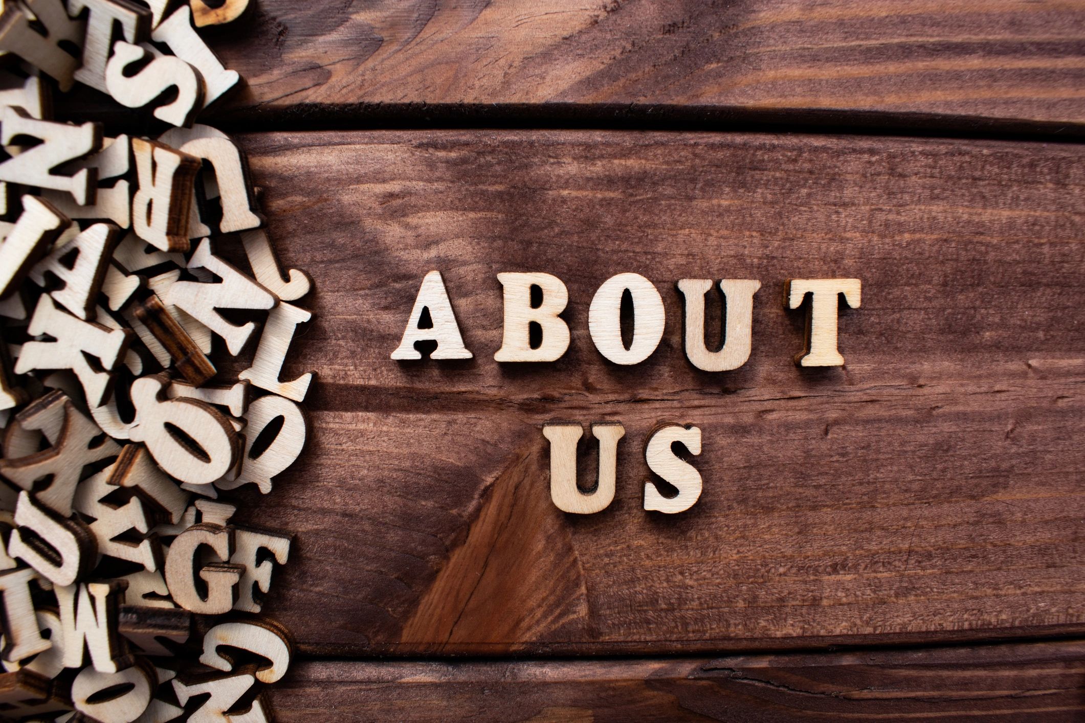 Wooden letters spelling 'ABOUT US' on a wooden surface.