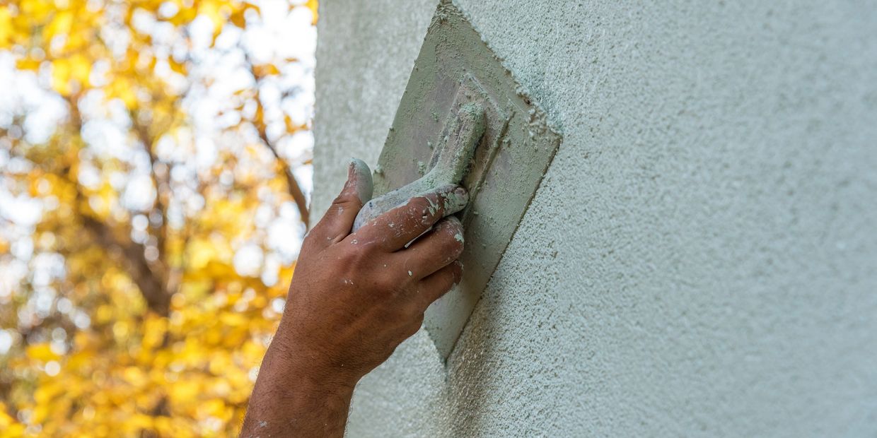 Hand smoothing plaster on a wall with a trowel. Expert Stucco Installation & Repair Built to Last